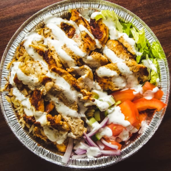 Hala's Grill chicken over rice with white sauce, lettuce, tomatoes, and red onions.